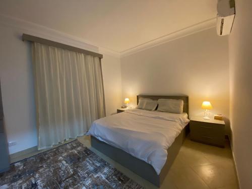 沙姆沙伊赫Renoviertes Luxusapartment Sunny Lakes 1 Sharm El-Sheikh nun auch für Langzeitmieter buchbar的一间卧室配有一张带两盏灯的床和一扇窗户。