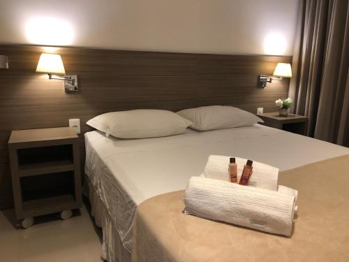 里约热内卢Apto tipo Flat Midas Riocentro - Barra da Tijuca- Barra olímpica的一间卧室配有一张床、两条毛巾和两盏灯。