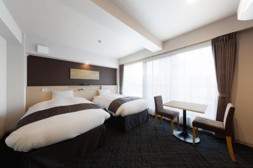 京都Hotel GOCO stay Kyoto Shijo Kawaramachi的酒店客房设有两张床和一张桌子。