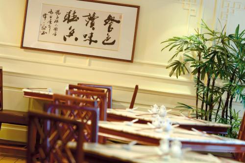 上海上海扬子江丽笙精选酒店的餐厅配有桌椅,墙上挂着一幅画