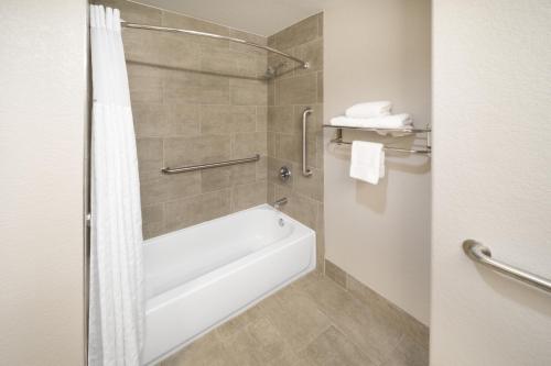 圣安东尼奥Days Inn & Suites by Wyndham San Antonio near Frost Bank Center的浴室配有白色浴缸和淋浴。