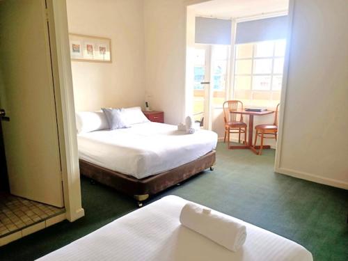 巴瑟斯特Knickerbocker Hotel的酒店客房带两张床和一张桌子以及椅子。