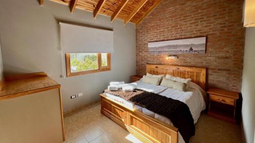 埃尔卡拉法特Del Glaciar Libertador Hotel的一间卧室设有一张床和砖墙