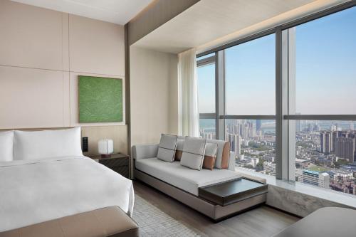 长沙长沙建鸿达JW万豪酒店的一间卧室配有一张床、一张沙发和一个大窗户