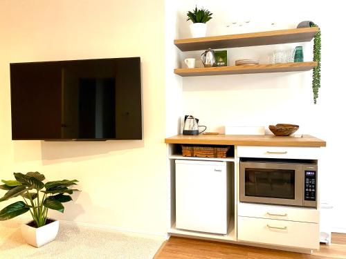 木麻黄Casuarina Beach 2 bedroom retreat的带微波炉的厨房和墙上的电视