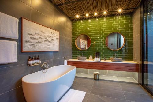 利文斯顿Mukwa River Lodge的带浴缸和绿色墙壁的浴室
