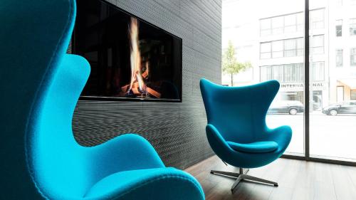 不莱梅不来梅莫泰一号酒店的两间蓝色椅子坐在带电视的房间