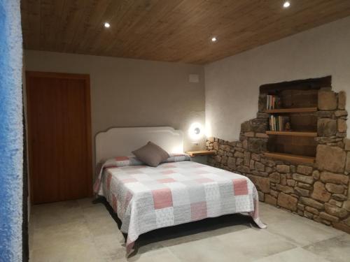 OlostCountry House El Permanyer的一间卧室设有一张床和石墙