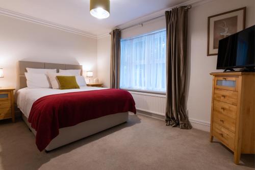 布拉克内尔Charnwood Guest House的一间卧室设有一张床、一台电视和一个窗口。