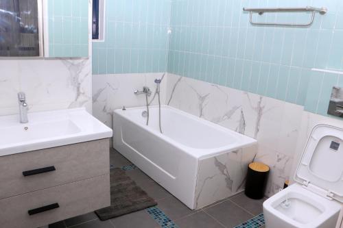 林贝Candide Guest House的带浴缸、盥洗盆和卫生间的浴室