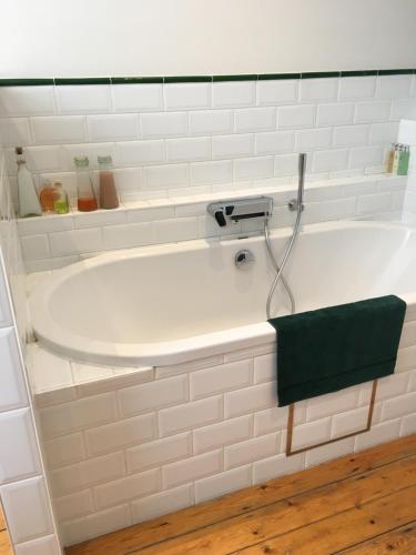 奥纲赖泽Overijse’s cosiest double room的白色浴缸,上面有绿毛巾
