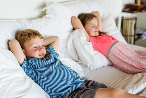 圣保罗湾城QAWRA Palace Resort & SPA的两个小孩躺在床上