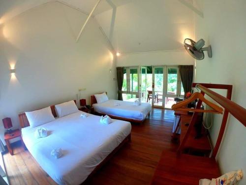 万荣Vang Vieng Eco Lodge的客房内设有两张床,铺有木地板,设有窗户。