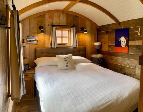 弗罗姆The Walnut Wagon in the heart of Mells.的一间带一张大床的卧室,位于带木墙的房间