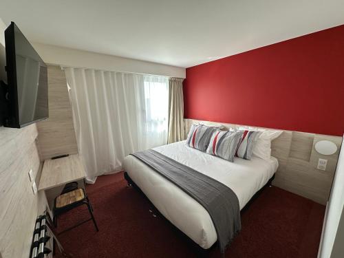 ChaurayHôtel Akena Chauray-Niort的酒店客房设有一张红色墙壁的大床