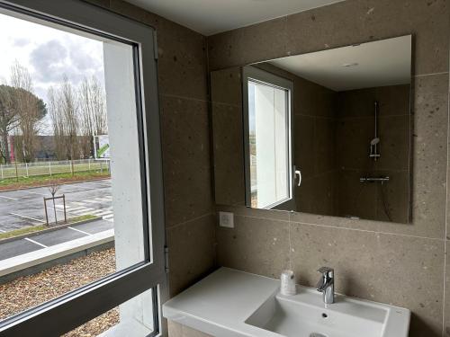 ChaurayHôtel Akena Chauray-Niort的一间带水槽和镜子的浴室以及窗户。