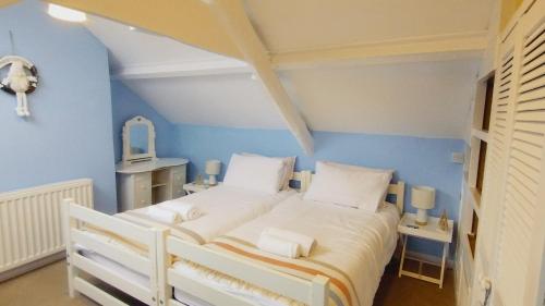 布里克瑟姆Pearl Cottage with parking pass - Grade II listed的卧室配有白色床和蓝色的墙壁