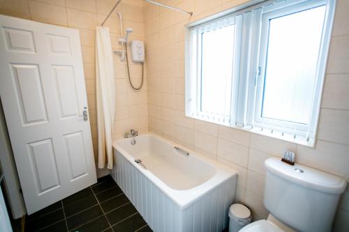 沃利Calder Cottage in The Ribble Valley的带浴缸、卫生间和窗户的浴室