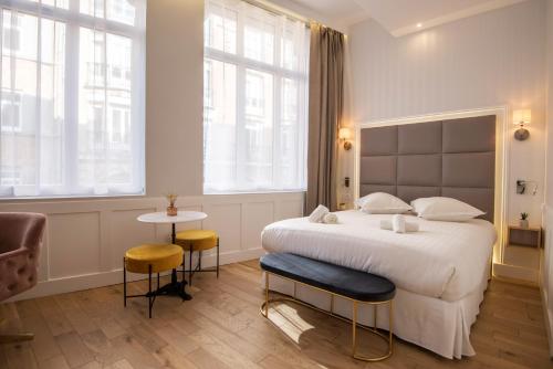 里尔Les Suites Faidherbe的一间卧室设有一张大床和两个窗户。