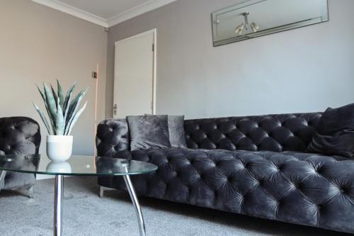伯明翰The Grey Haven Birmingham的客厅里一张黑色皮沙发,配有玻璃桌