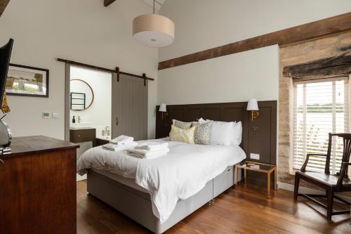 斯坦福德Linseed Barn- Stamford Holiday Cottages的卧室配有一张白色大床和一张书桌