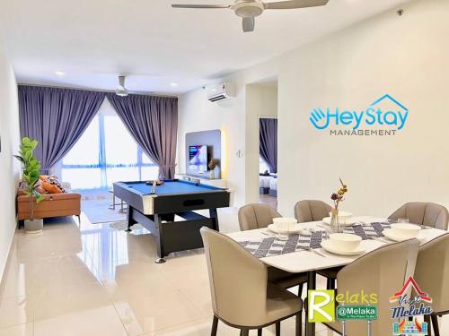 马六甲The Apple Residence By Heystay Management的一间带乒乓球桌的客厅和一间带游泳池的用餐室