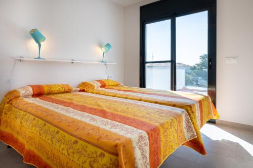 托里代巴拉AT033 La Siesta的一间卧室配有两张带橙色和黄色毯子的床