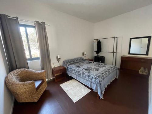 明德卢Tia Nita Apartamentos的卧室配有床、椅子和窗户。