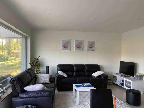 RimboTrevlig stuga med uteplats的客厅配有黑色真皮沙发和电视