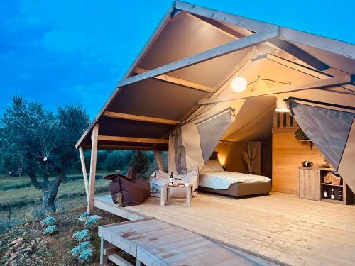 格罗塞托Glamping Grancia的一个带一张床和一个木制甲板的大型帐篷