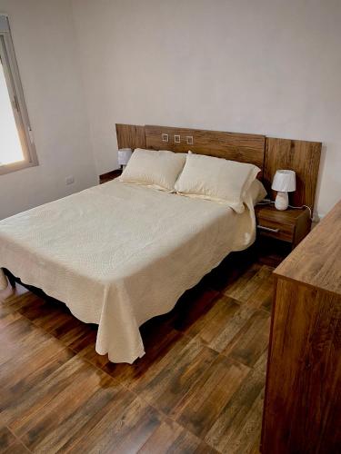 皮里亚波利斯Casa pet friendly, se reserva con seña的一间卧室配有一张铺有木地板的白色床单。