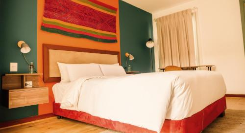 库斯科Viajero Kokopelli Cusco Hostel的卧室配有白色的床和色彩缤纷的墙壁