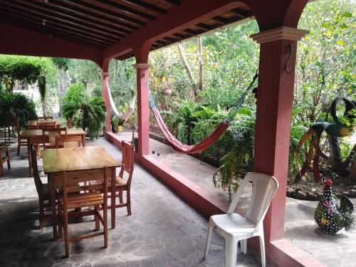 Los PotrerillosHostal Izacalli的门廊配有桌椅和吊床