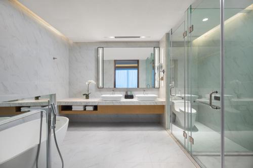 上海上海虹桥维景酒店的浴室设有2个盥洗盆、淋浴和镜子。
