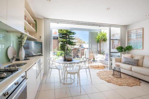 悉尼HolidayRento Boutique Terrace Apt in Bondi Beach的厨房以及带桌椅的起居室。