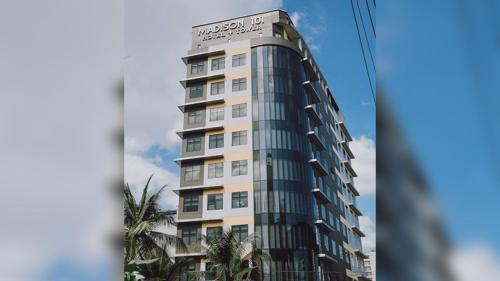 马尼拉麦迪逊塔楼101酒店的一座高大的建筑,前面有棕榈树