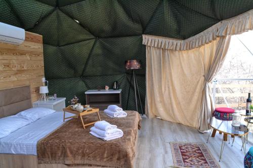 Zemo KhodasheniBerkheva Glamping - ბერხევა გლემპინგი的一间卧室设有绿墙,床上配有毛巾