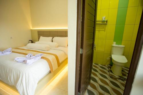 TarunaHAYANA HOTEL的一间带两张床的卧室和一间带卫生间的浴室