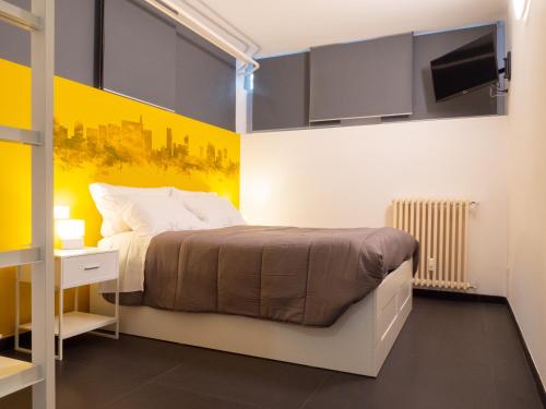 米兰Blocco Sauli的一间卧室设有一张床和黄色的墙壁