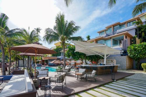 攀瓦海滩Bandara Villas, Phuket的一个带桌椅和遮阳伞的户外庭院。