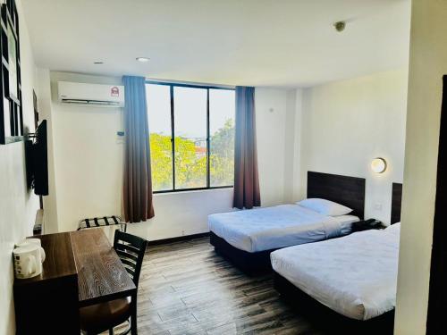 瓜埠Langkawi Baron Hotel - renovated 2023的酒店客房设有两张床和一张桌子。