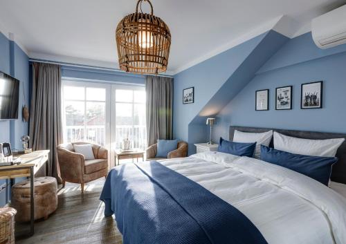 蒂门多弗施特兰德Seventy Seven Beach Hotel的一间卧室设有蓝色的墙壁、一张床和一张书桌