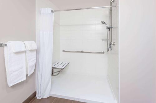 圣约翰堡Microtel Inn & Suites by Wyndham Fort Saint John的带淋浴和白色毛巾的浴室