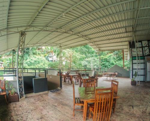 康提Kandy Forest Villa Hotel的庭院设有木桌、椅子和树木