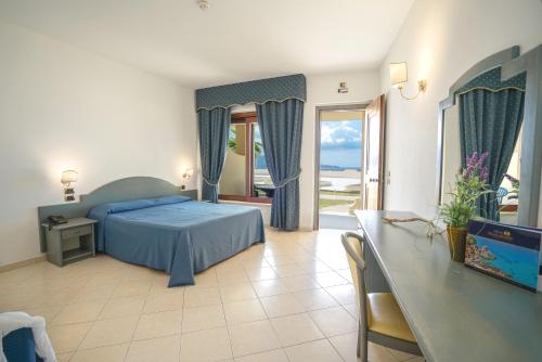 赞布隆内思科格利奥德尔塞拉利昂酒店的一间卧室配有蓝色的床、一张桌子和一个窗户。