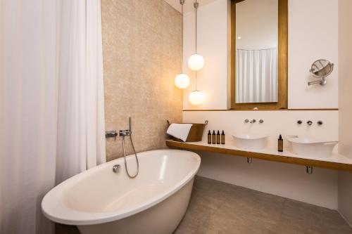 维也纳霍尔曼贝勒塔格设计精品酒店的带浴缸、两个盥洗盆和镜子的浴室