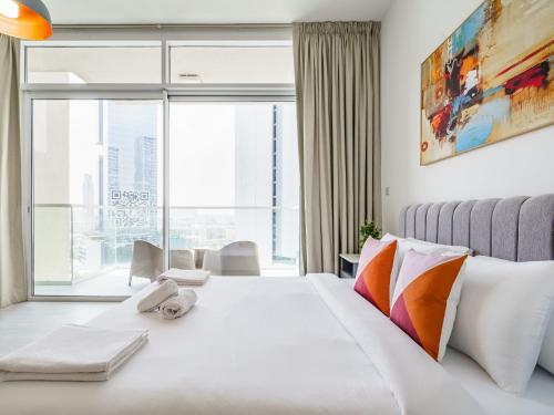 迪拜Luxury Studio with Pool View in Vibrant Community的卧室配有白色的床和大窗户
