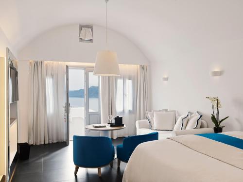 伊亚Katikies Santorini - The Leading Hotels Of The World的酒店客房带一张床、一张桌子和椅子