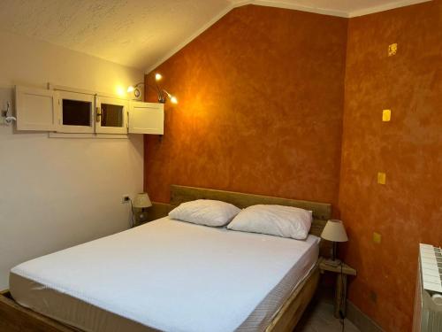 塞里纳Paradise La Tana的一间卧室配有一张带白色床单和橙色墙壁的床。