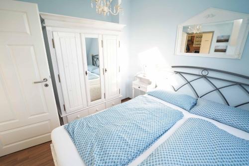 多尔努姆Ferienwohnung Sonne&Meer的卧室配有蓝色和白色的床和镜子